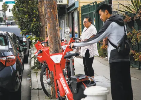  ?? Photos by Nicole Boliaux / The Chronicle ?? Yvonne Tam (left) and Franco Huang check out Social Bicycles’ Jump bikes, part of a pilot e-bike-sharing program in San Francisco.