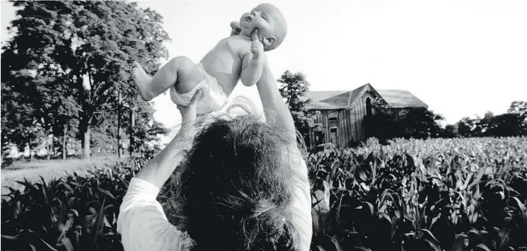  ?? PHOTOS: LARRY TOWELL/MAGNUM PHOTOS ?? Above, in Ontario’s Lambton County, 1993 — months-old Isaac Towell, being held above a corn field a few hundred yards down the road from his home. At top, from left, San Salvador, 1991 — a girl comforts her mother at the grave of her son, who was...