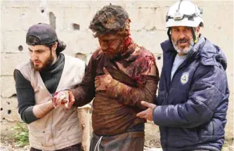  ??  ?? DARAA, Syria: Members of the Syrian civil defense volunteers, also known as the White Helmets, help a man after removing him from the rubble of his house following an air strike by government forces on a rebel-held area in this southern city yesterday....