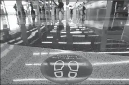  ?? JOHN J. KIM/CHICAGO TRIBUNE ?? A floor sign reminds travelers to keep social distancing measures in Terminal 3 at O&apos;Hare Internatio­nal Airport in Chicago. A man is now on electronic monitoring for staying undetected at the airport for three months in a restricted location.