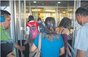  ?? Bebeto Matthews, The Associated Press ?? Patrons enter the Queens Central Library last month in New York City just as doors open to start the day.