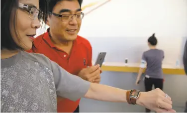  ?? Eric Risberg / Associated Press ?? Shawn Wang and husband Gary Chen of Taiwan try out an Apple Watch at the Apple Store at Stanford Shopping Center in Palo Alto. Apple does not break out separate sales figures for its much-hyped Watch.