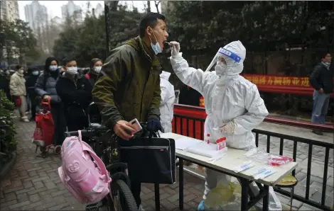  ?? CHINATOPIX VIA AP ?? A man holding his bicycle with a school bag on it gets a throat swab during a mass COVID-19test Feb. 22at a residentia­l compound in Wuhan in central China’s Hubei province.