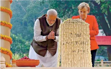 ??  ?? German Chancellor Angela Merkel and India’s Prime Minister Narendra Modi pay their tributes at the Mahatma Gandhi memorial during their visit to Gandhi Smriti in New Delhi on Friday.