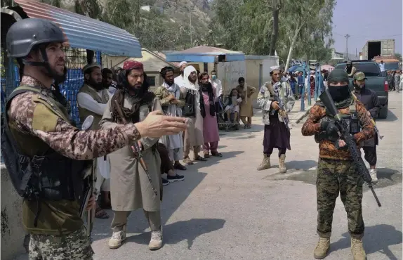  ?? Ap pHotos ?? AT THE BORDER: A Pakistani soldier, left, and Taliban fighters stand guard on their sides of the border crossing at Torkham, Pakistan. Below, Taliban special forces fighters stand guard outside the airport in Kabul.