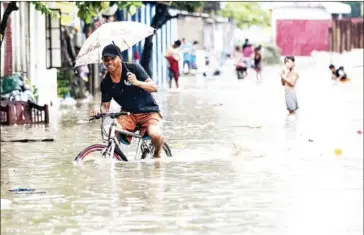  ?? NOEL CELIS/AFP ?? A man on Sunday pedals his bicycle through a flooded street due to continuous rains caused by tropical depression Josie in Marikina, east of Manila.