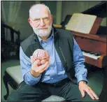  ?? ADAM SCOURFIELD/BBC/AP PHOTO ?? In this 2007 photo, neurologis­t Oliver Sacks poses at a piano while holding a model of a brain at the Chemistry Auditorium, University College London in London.