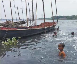  ??  ?? Des enfants se baignent dans le Buriganga, la rivière qui traverse Dhaka et qui a été tuée au fil des ans par les déversemen­ts industriel­s.