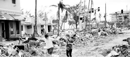  ?? AP ?? Jake Moses (left), 19, and Heather Jones, 18, of Fort Myers, explore a section of destroyed businesses at Fort Myers Beach, Florida, on Thursday, September 29, following the passage of Hurricane Ian.