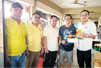  ?? ?? Ching Yong (right) and his team distribute Chinese New Year goodies to a member of the public during the mobile service session.