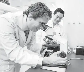  ?? JOSE M. OSORIO/CHICAGO TRIBUNE ?? Dr. Adam Sonabend, the senior author of a recent study in the Nature Center journal, looks over tumor samples under a microscope Dec. 1 with Dr. Victor Andres Arrieta, another author of the study, at the Simpson Querrey Biomedical Research Center in Chicago.