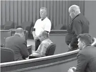  ?? Staff photo by Lynn LaRowe ?? ■ Tonny Ezernack, center, sits with hands cuffed behind his back as his lawyer, Butch Dunbar, speaks with him as Bowie County deputies stand nearby. Ezernack cursed at a prosecutor and disrupted closing remarks in the trial with verbal outbursts.