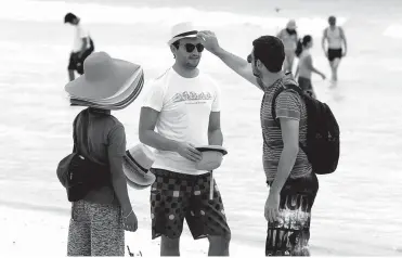  ??  ?? Foreign tourists try hats being sold by vendors who will be affected by the closure of Boracay island due to the clean-up and rehabilita­tion works starting April 26. The rehabilita­tion works include a drainage audit to probe the wastewater discharge in...