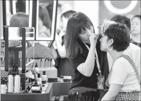  ?? NIU JING / FOR CHINA DAILY ?? A consumer tries new cosmetics at a shopping mall in Beijing.