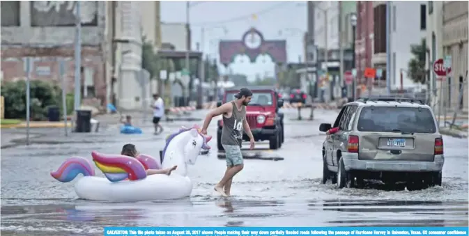  ??  ?? GALVESTON: This file photo taken on August 26, 2017 shows People making their way down partially flooded roads following the passage of Hurricane Harvey in Galveston, Texas. US consumer confidence recovered from the hurricane-induced doldrums last...