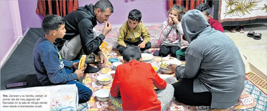  ?? ?? Tiro. Zamzam y su familia, comen primer día del mes sagrado del Ramadán en la sala de refugio donde viven desde el bombardeo israelí. el