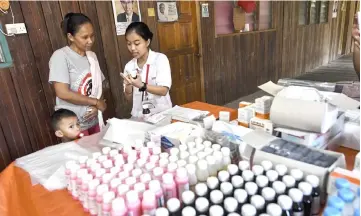  ?? — Bernama photo ?? A volunteer explains to a villager the proper intake of her medicines.
