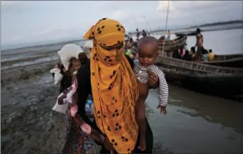  ??  ?? In this Sept. 21 photo, a Rohingya woman carries a child after crossing a stream on a small boat near Cox’s Bazar’s Dakhinpara area, Bangladesh. AP PHOTO/BERNAT ARMANGUE