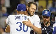  ?? LOS ANGELES TIMES ?? Dodgers pitcher Clayton Kershaw embraces manager Dave Roberts after a 3-0 defeat of the Braves in Game 2 of the NLDS. The Dodgers won in four.