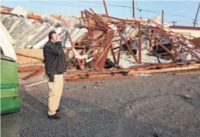  ?? MIKE SIMONS/AP ?? Justin Sloggett looks over the destroyed warehouse of his parents’ furniture store Sunday in Sapulpa, Okla.