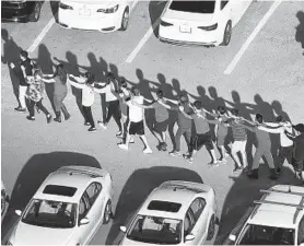  ?? JOE RAEDLE/GETTY ?? Students and others are brought out of the Marjory Stoneman Douglas High School after a mass shooting on Feb. 14, 2018, in Parkland, Florida.