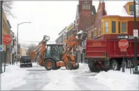  ??  ?? Crews load snow into trucks at Gay and North New streets in West Chester during the tail end of Tuesday’s storm.