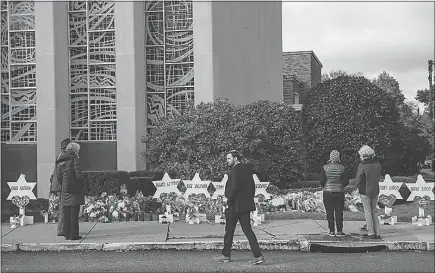  ?? MICHAEL HENNINGER / THE NEW YORK TIMES ?? Mourners visit a makeshift memorial Monday outside the Tree of Life Congregati­on, where 11 people died at the synagogue during a shooting rampage Saturday in Pittsburgh. Survivors and relatives of the victims were still struggling to come to terms with the enormity of the loss Monday as the suspect appeared in court for the first time.