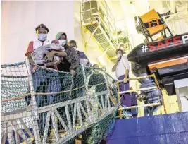  ?? MASSIMO DI NONNO AP ?? Migrants disembark from the Norway-flagged Geo Barents rescue ship carrying 572 migrants, in Catania’s port, Sicily, on Sunday. The Geo Barents and the German-flagged Humanity have been allowed to disembark what the Italian authoritie­s defined “vulnerable people” and minors while other two ships carrying rescued migrants remained at sea.