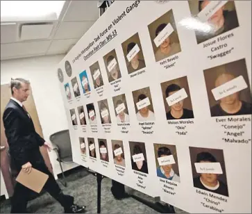  ?? Al Seib Los Angeles Times ?? PAUL DELACOURT, FBI assistant director in charge of the agency in Los Angeles, walks past photos of MS-13 gang members at a news conference announcing the indictment­s of 22 members of the group.