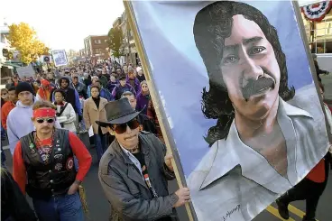  ?? Associated Press ?? ■ Marchers carry a large painting of jailed American Indian Leonard Peltier during a march Nov. 22, 2001, for the National Day of Mourning in Plymouth, Mass. United American Indians of New England held its first National Day of Mourning in 1970. Tribes again plan to gather at noon on a windswept hill overlookin­g Plymouth Rock on Thanksgivi­ng Day.