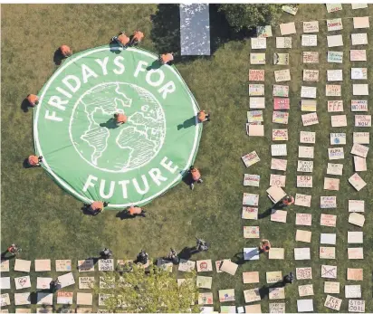  ?? FOTO: DPA ?? Corona hat auch die Bewegung „Fridays for Future“ein Stück weit zurückgewo­rfen. Aktivisten legten kürzlich Protestpla­kate auf der Wiese vor dem Berliner Reichstag aus. Sie verlegen ihren Klimastrei­k aktuell verstärkt ins Internet.