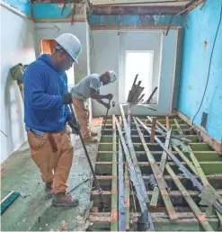  ??  ?? Orlando Simmons, left, and Damon Toogood remove planks of flooring from an abandoned row home in Baltimore.