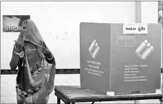  ??  ?? A woman covers her face as she leaves a polling booth after casting her vote during the first phase of state assembly election in Limbdi town of Surendrana­gar district in the western state of Gujarat, India. — Reuters photos