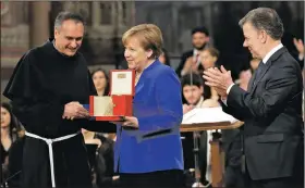  ?? AP/ALESSANDRA TARANTINO ?? The Rev. Mauro Gambetti presents the St. Francis Lamp peace prize to German Chancellor Angela Merkel on Saturday in St. Francis’ Basilica in Assisi, Italy. At right is Colombian President Juan Manuel Santos, winner of the 2016 Nobel Peace Prize, who...