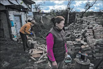  ?? Alex Babenko The Associated Press ?? Artem Yarema, 13, chops wood, while his mother, Tetiana Yarema, 48, stands in front of the family’s house in Moshchun, near Kyiv, Ukraine. Like millions of other Ukrainians touched by Russia’s war, winter is an especially challengin­g time.