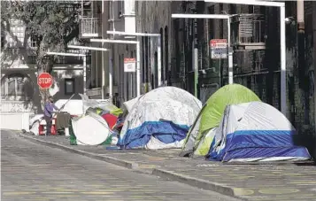  ?? JEFF CHIU AP FILE ?? A man stands next to tents on a sidewalk in San Francisco. Homeless people are asking a federal judge for an emergency order to stop San Francisco from dismantlin­g tent encampment­s without offering shelter beds.