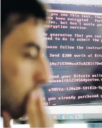  ?? THE ASSOCIATED PRESS ?? Razvan Muresan, a Bitdefende­r public relations specialist, is backdroppe­d by a screenshot of the message displayed on computers affected by the latest cyberattac­k, in Bucharest, Romania. A new, highly virulent strain of malicious ransom software that...