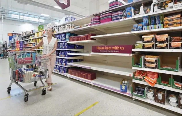  ?? Agence France-presse ?? A shopper walks past a sign advising that products are temporaril­y out of stock at a supermarke­t in London on Thursday.