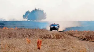  ??  ?? A firetruck drives across a burning field Sunday near SE 134.