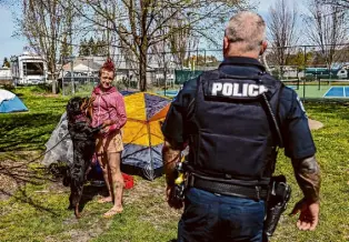  ?? ?? During his daily rounds of homeless encampment­s, police officer Tim Artoff checks on Cat and her dog, Sugar Mama, in Morrison Park.