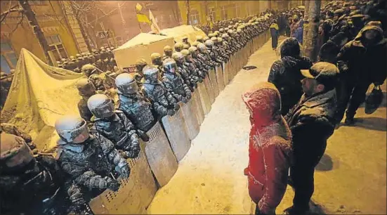  ?? SERGEI GRITS / AP ?? Cara a cara. El presidente Yanukóvich desplegó ayer las fuerzas antidistur­bios en los principale­s edificios del poder en Kíev (sede del Gobierno, en la fotografía), encaradas a los cerca de diez mil manifestan­tes que seguían en las calles