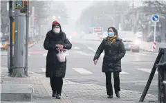  ?? AFP ?? Women wear face masks to protect against coronaviru­s as they walk on a sidewalk on a polluted day in Beijing, China.