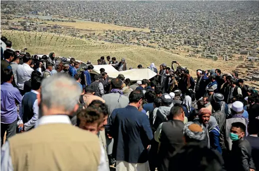  ?? AP ?? Afghan men bury a victim of deadly bombings on Saturday near a school, at a cemetery west of Kabul.