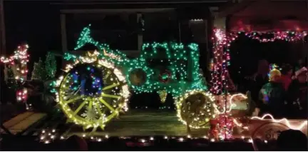  ?? BY PAUL POST ?? An antique green tractor with gold colored wheels lit up the night.