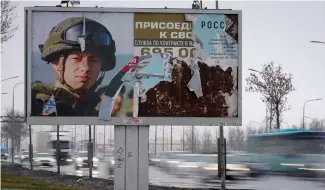  ?? ?? Des voitures passent devant un panneau publicitai­re à SaintPéter­sbourg promouvant le service militaire contractue­l dans l'armée russe.