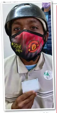  ??  ?? behind his mask with his
Gary Gabier smiles vaccinatio­n card.