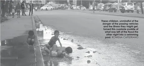  ?? ROWENA CAPISTRANO ?? These children, unmindful of the danger of the passing vehicles and the illness they might get, turned this roadside puddle of what was left of the flood the other night into a swimming pool.