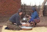  ?? ROY NKOSI/AP ?? Cameron Beach, left, sieves maize flour as she helps prepare a meal July 23 in Dedza, near Lilongwe, Malawi. Beach, a former Peace Corps volunteer, is living in rural Malawi teaching English at a rural high school where she had been sent by the United States government 18-months before COVID-19 began sweeping the world.