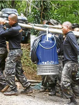  ?? —AP ?? HEAVY BURDEN Soldiers carry a pump to help drain the rising flood water in a cave where 12 boys and their soccer coach have been trapped since June 23, in Mae Sai, Chiang Rai province, in northern Thailand on Friday. Thai authoritie­s are racing to pump...