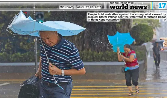  ?? AP ?? People hold umbrellas against the strong wind caused by Tropical Storm Pakhar near the waterfront of Victoria Habor in Hong Kong yesterday.